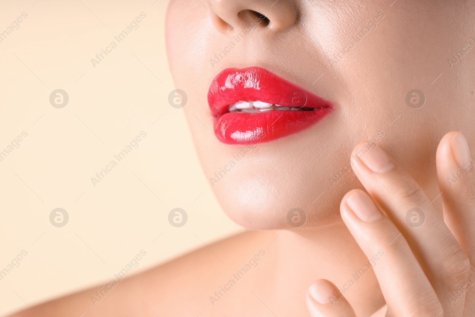 Photo of Woman with beautiful red lipstick on her lips against beige background, macro view. Space for text