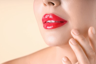 Photo of Woman with beautiful red lipstick on her lips against beige background, macro view. Space for text