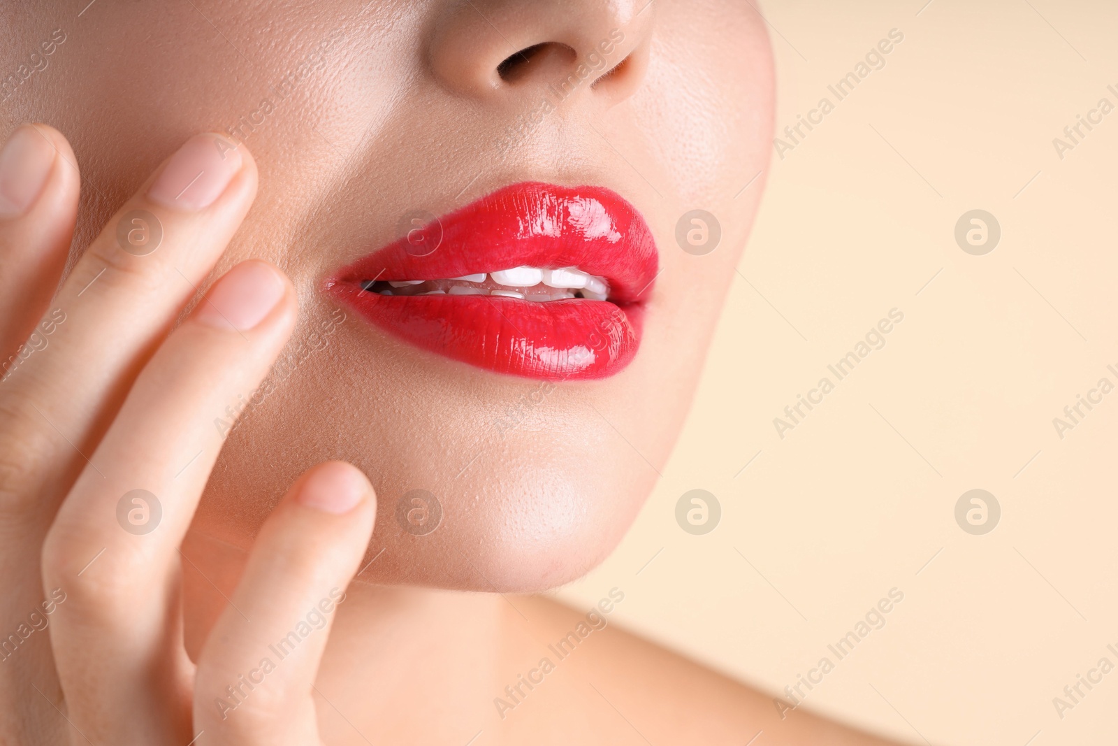 Photo of Woman with beautiful red lipstick on her lips against beige background, macro view