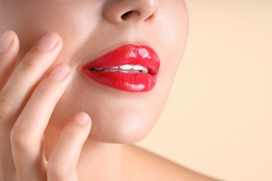Photo of Woman with beautiful red lipstick on her lips against beige background, macro view
