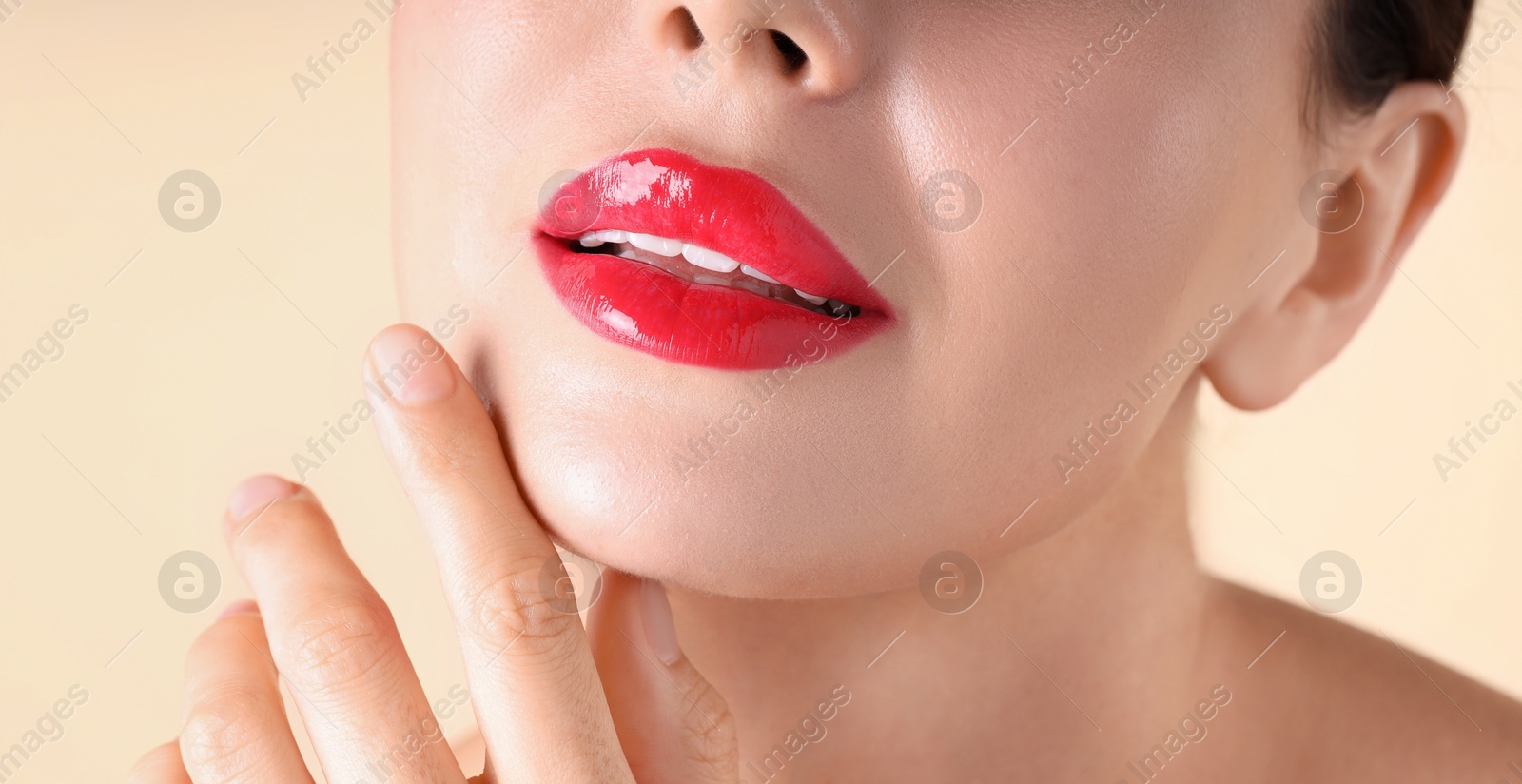 Photo of Woman with beautiful red lipstick on her lips against beige background, macro view