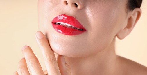 Photo of Woman with beautiful red lipstick on her lips against beige background, macro view