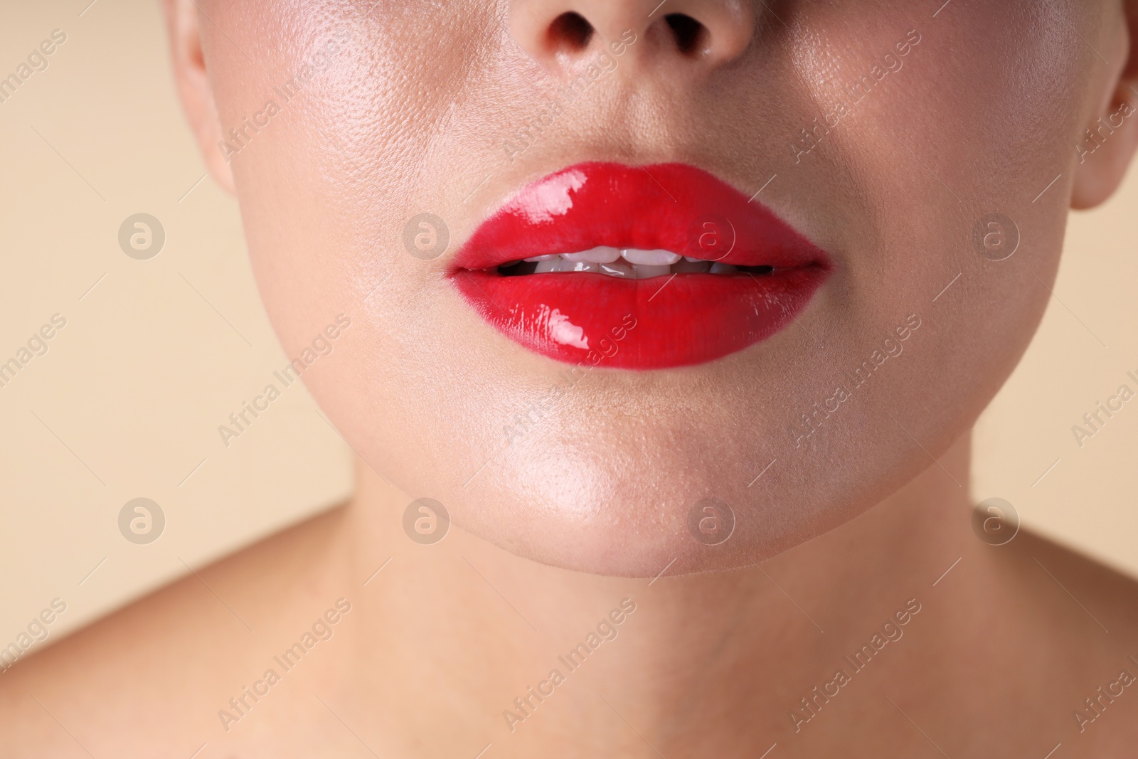 Photo of Woman with beautiful red lipstick on her lips against beige background, macro view