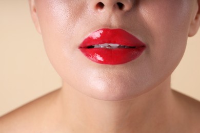 Photo of Woman with beautiful red lipstick on her lips against beige background, macro view