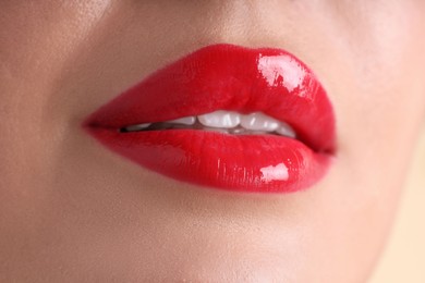Photo of Woman with beautiful red lipstick on her lips against beige background, macro view