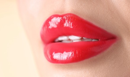 Photo of Woman with beautiful red lipstick on her lips against beige background, macro view