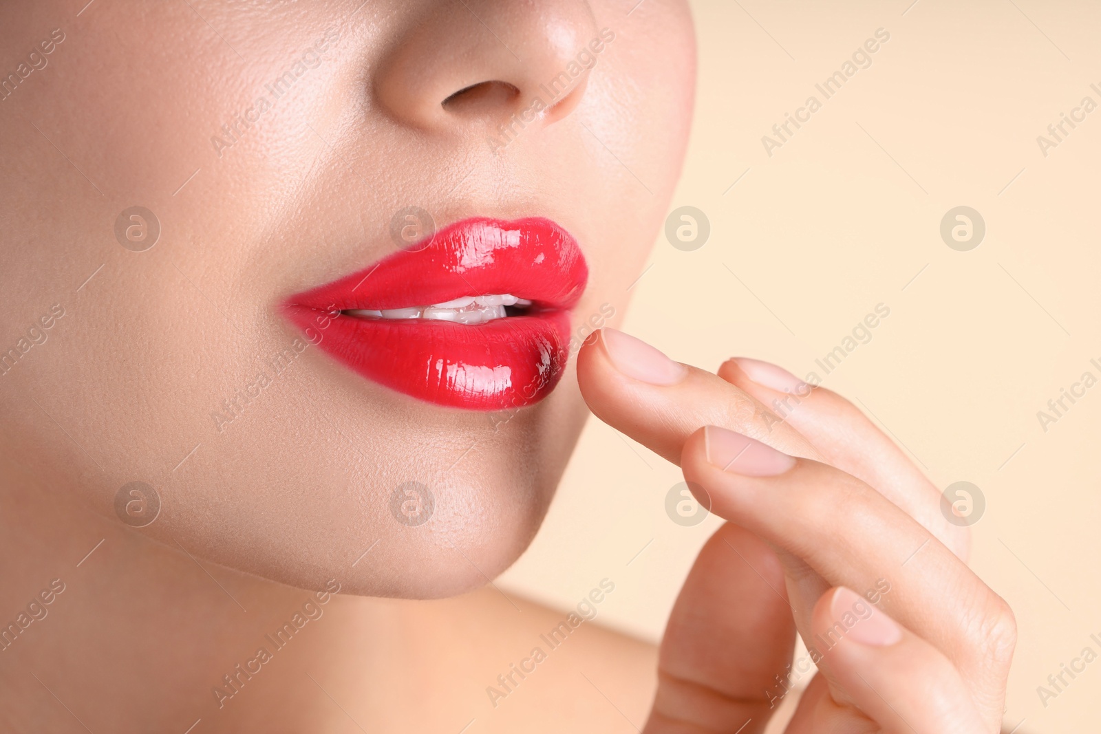 Photo of Woman with beautiful red lipstick on her lips against beige background, macro view