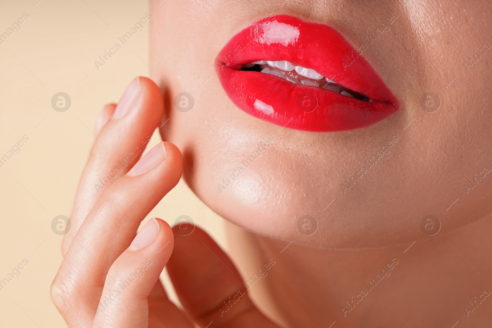 Photo of Woman with beautiful red lipstick on her lips against beige background, macro view