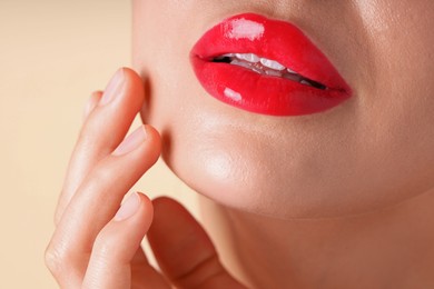Photo of Woman with beautiful red lipstick on her lips against beige background, macro view