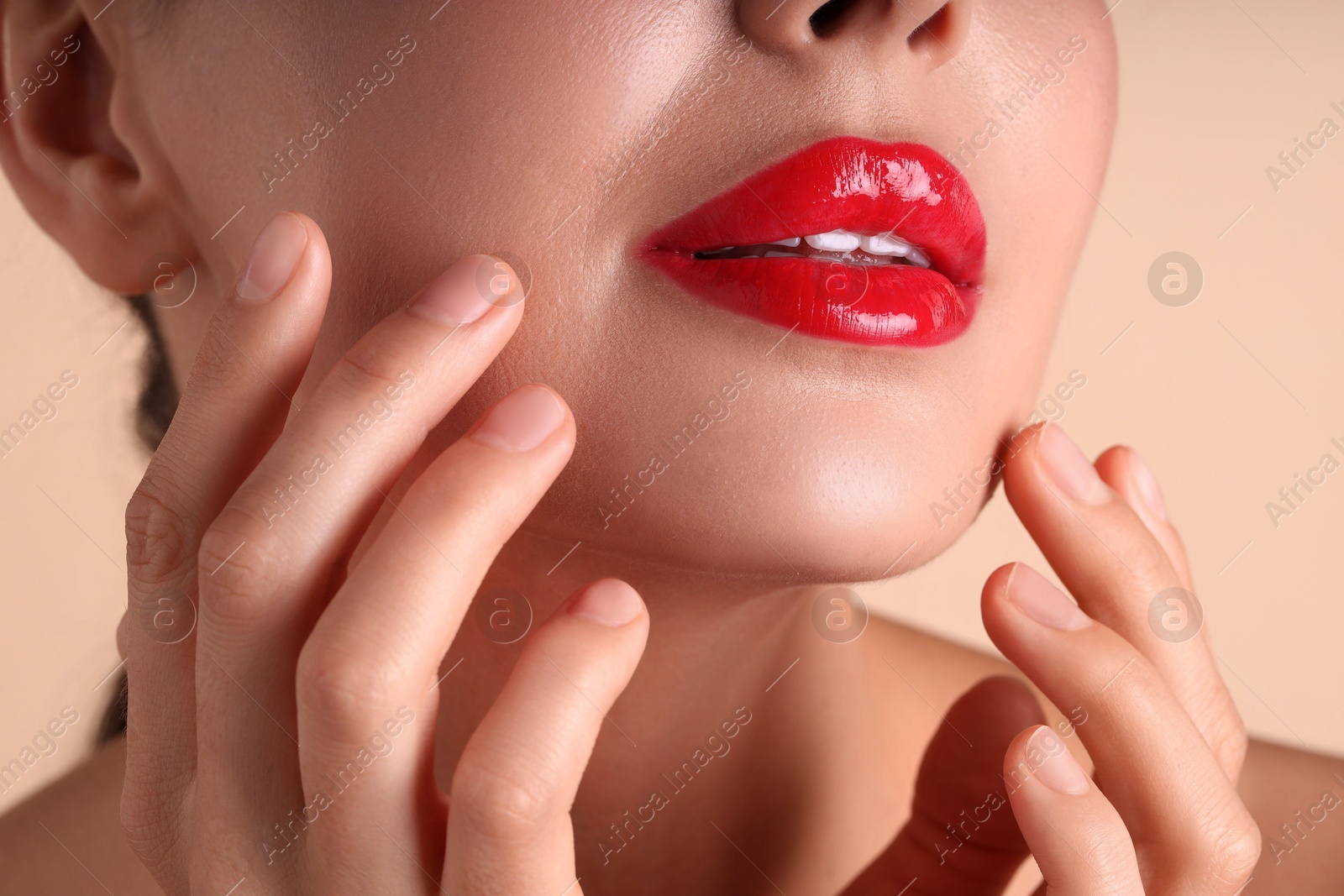Photo of Woman with beautiful red lipstick on her lips against beige background, macro view