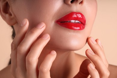 Photo of Woman with beautiful red lipstick on her lips against beige background, macro view