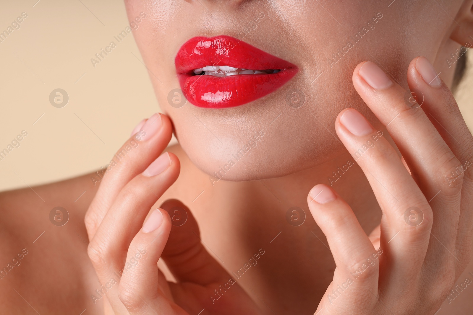 Photo of Woman with beautiful red lipstick on her lips against beige background, macro view