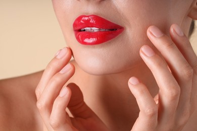 Photo of Woman with beautiful red lipstick on her lips against beige background, macro view