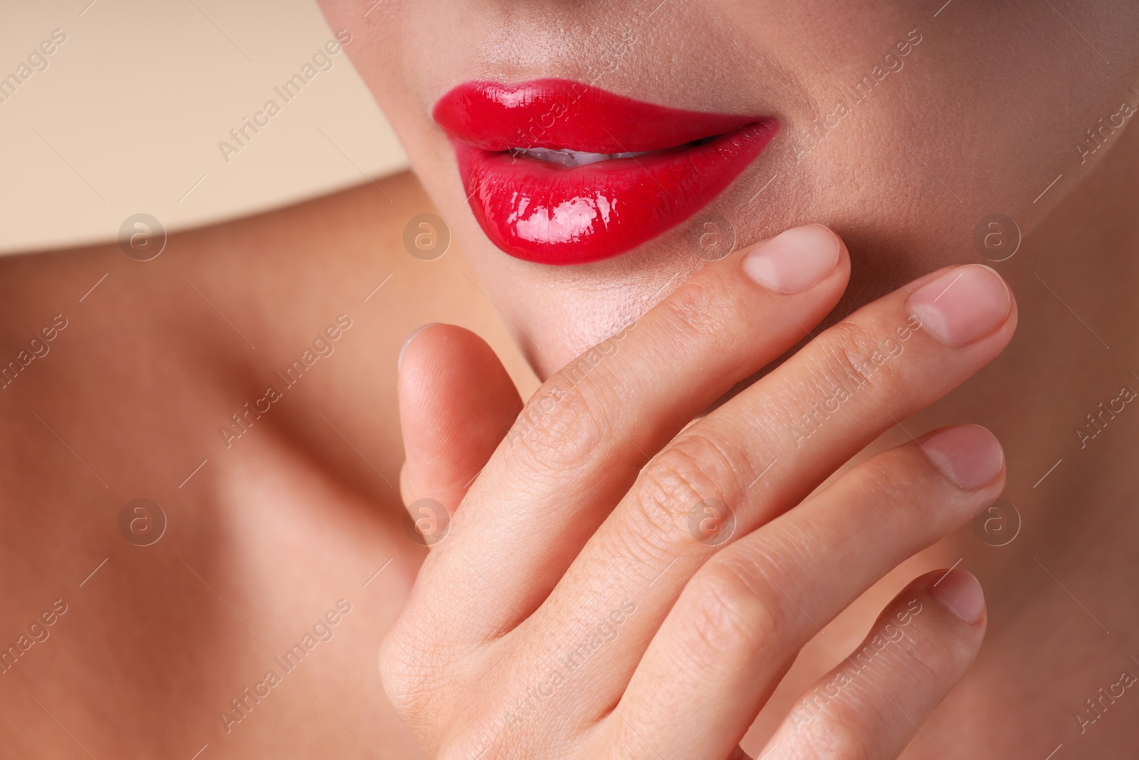 Photo of Woman with beautiful red lipstick on her lips against beige background, macro view
