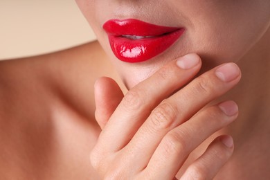 Photo of Woman with beautiful red lipstick on her lips against beige background, macro view