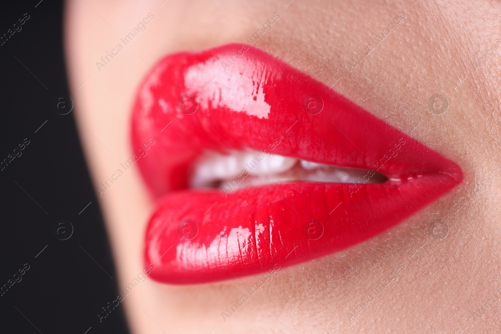 Photo of Woman with beautiful red lipstick on her lips against black background, macro view