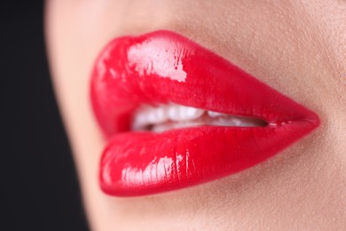 Photo of Woman with beautiful red lipstick on her lips against black background, macro view
