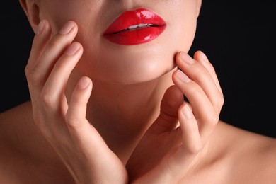 Photo of Woman with beautiful red lipstick on her lips against black background, macro view