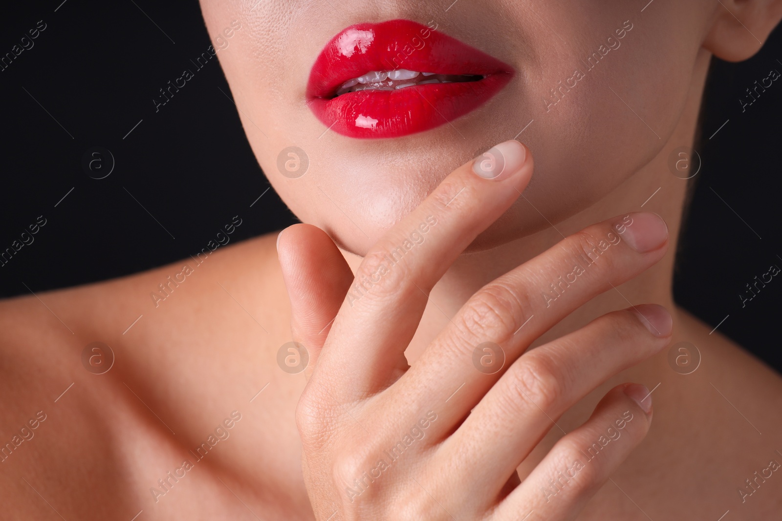 Photo of Woman with beautiful red lipstick on her lips against black background, macro view