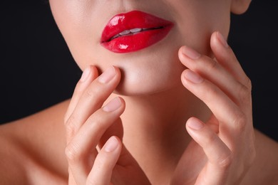 Photo of Woman with beautiful red lipstick on her lips against black background, macro view
