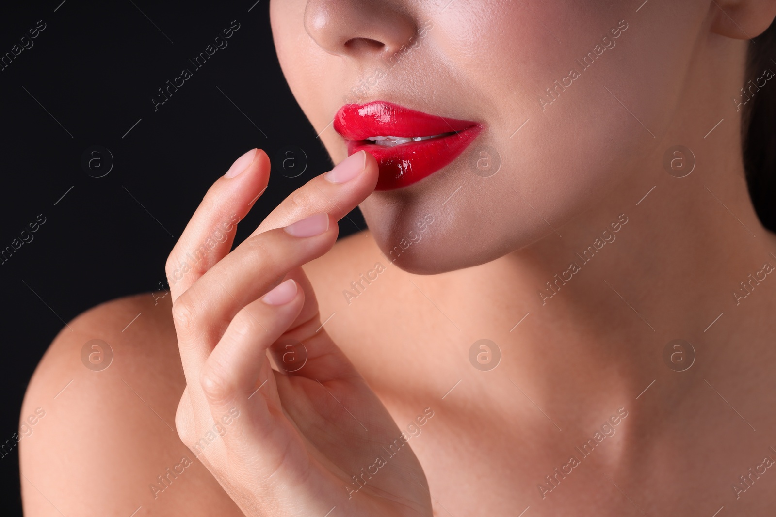 Photo of Woman with beautiful red lipstick on her lips against black background, macro view