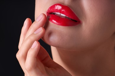 Photo of Woman with beautiful red lipstick on her lips against black background, macro view