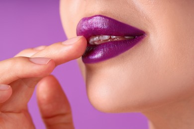 Photo of Woman with bright lipstick on purple background, macro view