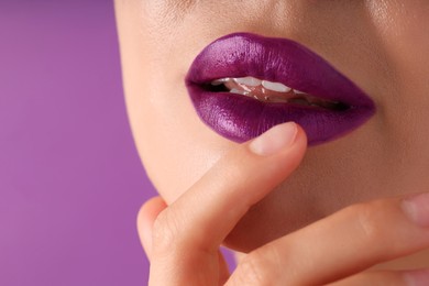 Photo of Woman with bright lipstick on purple background, macro view