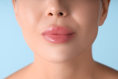 Photo of Woman with beautiful lips on light blue background, macro view