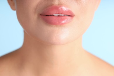 Photo of Woman with beautiful lips on light blue background, macro view