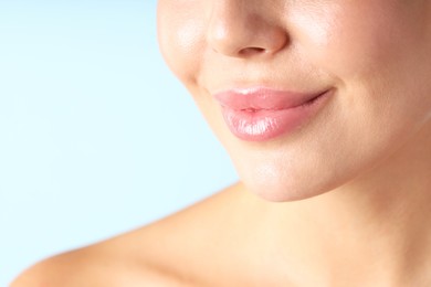 Photo of Woman with beautiful lips on light blue background, macro view
