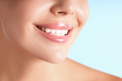 Photo of Woman with beautiful lips on light blue background, macro view