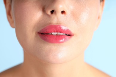 Photo of Woman with beautiful pink lipstick on her lips against light blue background, macro view