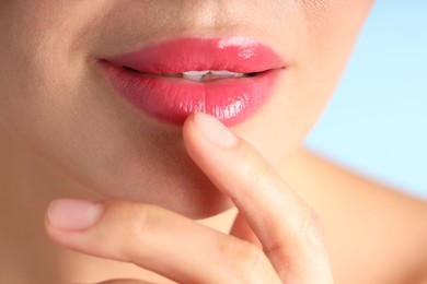 Photo of Woman with beautiful pink lipstick on her lips against light blue background, macro view
