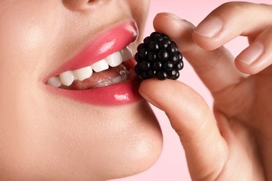 Photo of Woman with beautiful lipstick on her lips and blackberry against pink background, macro view