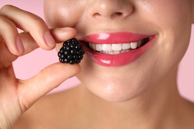 Photo of Woman with beautiful lipstick on her lips and blackberry against pink background, macro view