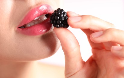 Photo of Woman with beautiful pink lipstick on her lips and blackberry against white background, macro view