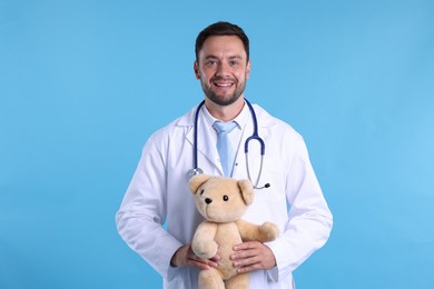 Photo of Pediatrician with teddy bear on light blue background