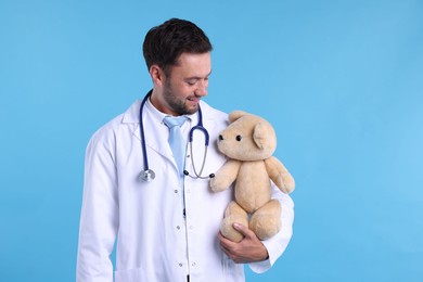 Photo of Pediatrician with teddy bear on light blue background