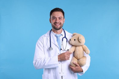 Photo of Pediatrician with teddy bear on light blue background