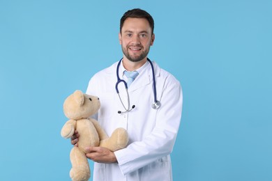 Photo of Pediatrician with teddy bear on light blue background