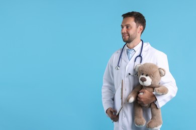 Photo of Pediatrician with teddy bear on light blue background. Space for text