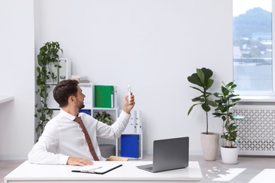 Photo of Man using remote to control air conditioner in office