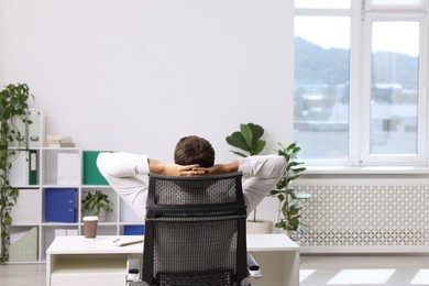 Photo of Man sitting at workplace in office with air conditioning, back view