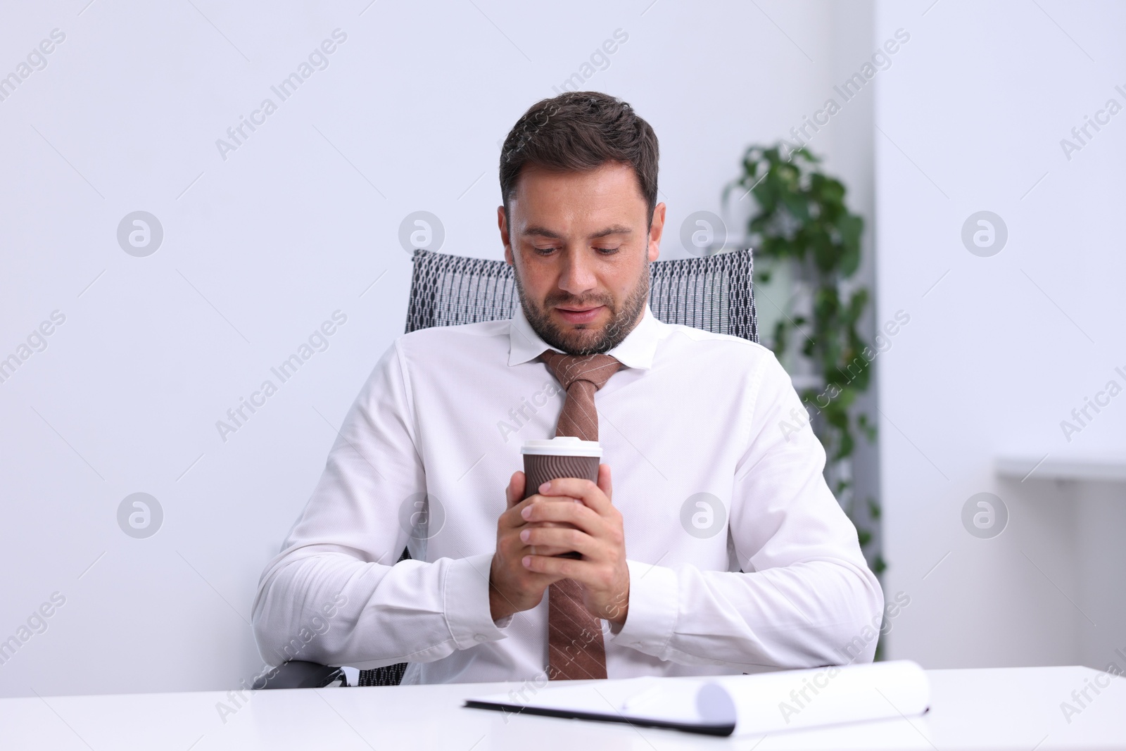 Photo of Air conditioning. Man with cup of hot drink suffering from cold temperature at workplace in office