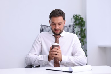Photo of Air conditioning. Man with cup of hot drink suffering from cold temperature at workplace in office