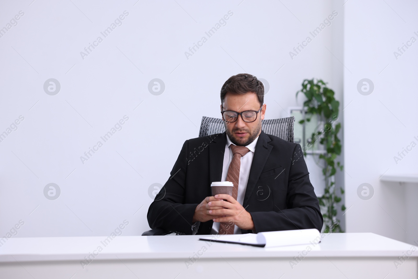 Photo of Air conditioning. Man with cup of hot drink suffering from cold temperature at workplace in office