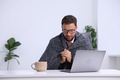 Photo of Air conditioning. Man with blanket suffering from cold temperature at workplace in office