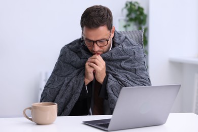 Photo of Air conditioning. Man with blanket suffering from cold temperature at workplace in office
