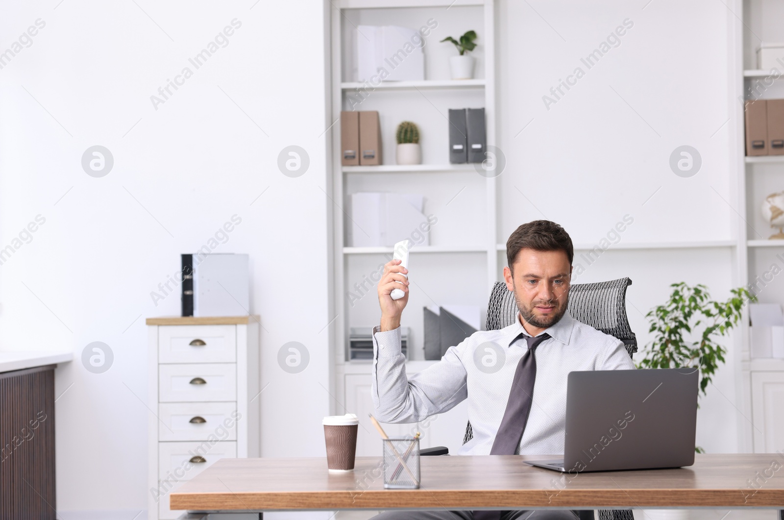 Photo of Man using remote to control air conditioner in office